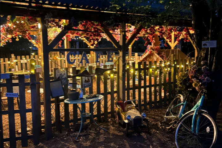 Outdoor café with string lights, colorful decorations, toy car, and bicycle at night.