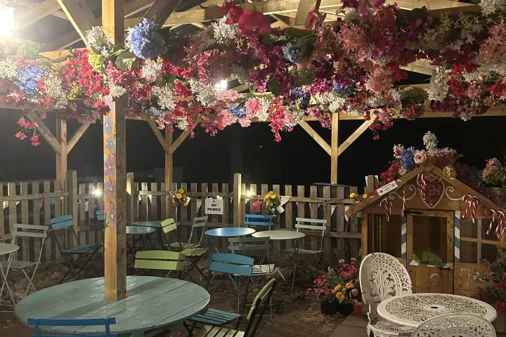 Patio with floral ceiling, colorful tables, and chairs at night.