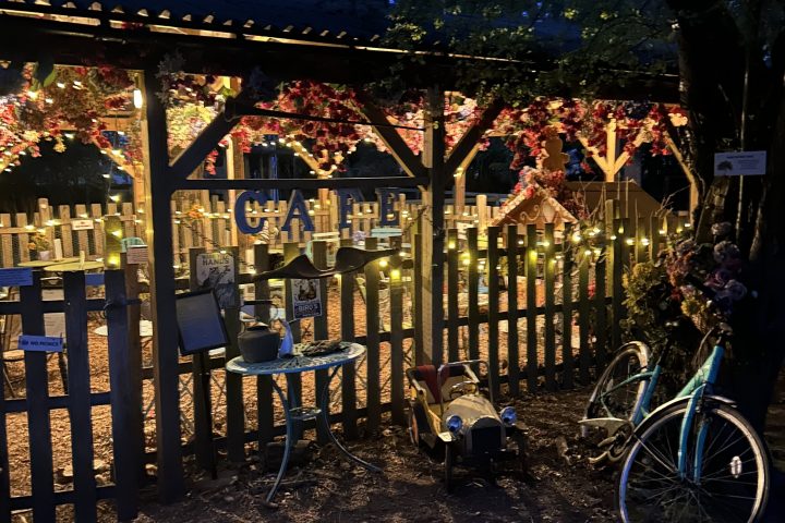 Outdoor patio with string lights, bicycle, and empty chairs at dusk.